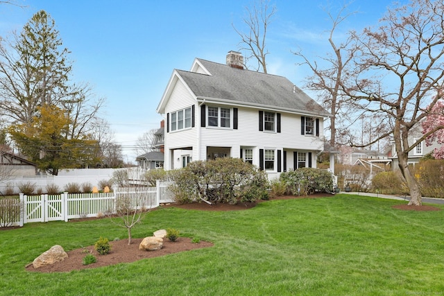 exterior space with a front lawn, fence private yard, a shingled roof, and a chimney
