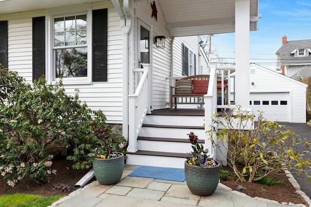 view of exterior entry featuring a porch and a detached garage