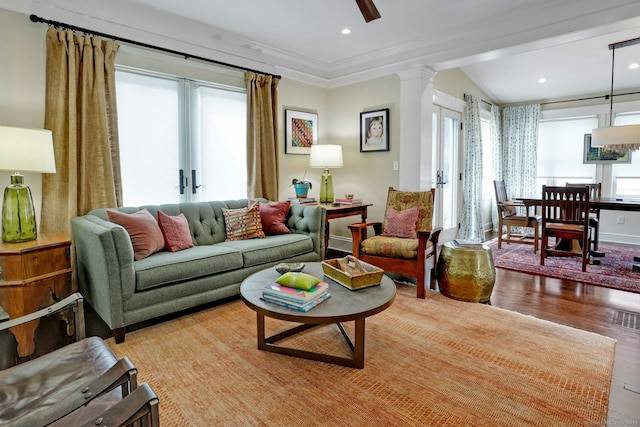 living area featuring crown molding, wood finished floors, visible vents, and a healthy amount of sunlight
