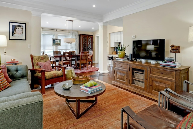living room featuring recessed lighting, wood finished floors, crown molding, and decorative columns