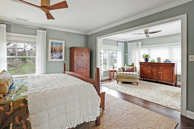 bedroom featuring visible vents, ornamental molding, dark wood-type flooring, baseboards, and ceiling fan