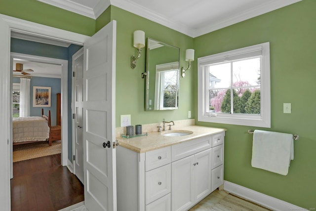 ensuite bathroom with wood finished floors, vanity, ensuite bath, crown molding, and baseboards