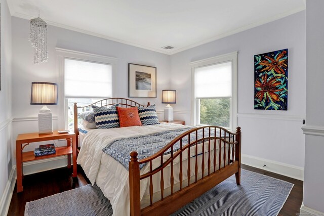 bedroom featuring wood finished floors, visible vents, and ornamental molding