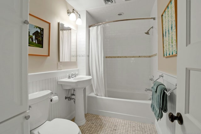 bathroom with visible vents, a wainscoted wall, shower / bath combo, and toilet