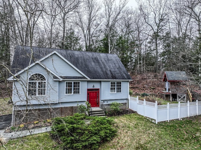 raised ranch featuring entry steps, a shingled roof, fence, and a front lawn