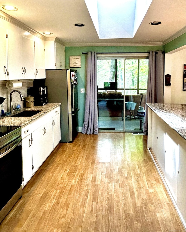 18 Paul St, Danbury, CT 06810 - kitchen with a sink, ornamental molding, stainless steel appliances, white cabinets, and light wood-type flooring
