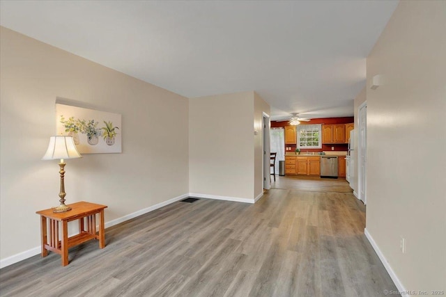 unfurnished living room with light wood-style floors, baseboards, and ceiling fan