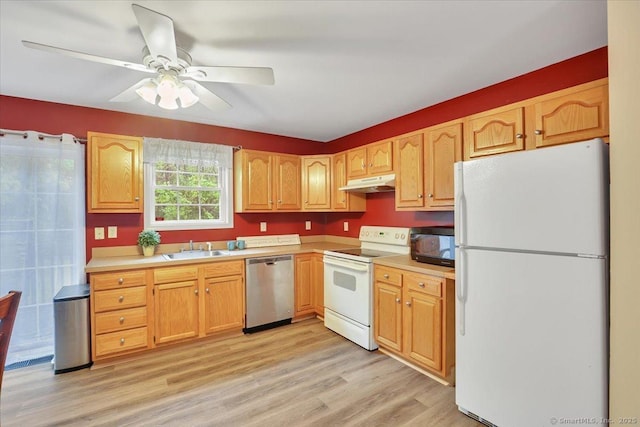 kitchen featuring white appliances, under cabinet range hood, a sink, light countertops, and light wood-type flooring