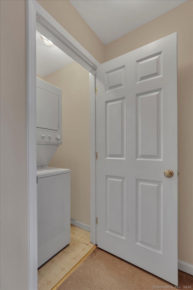 clothes washing area with stacked washer / dryer and baseboards