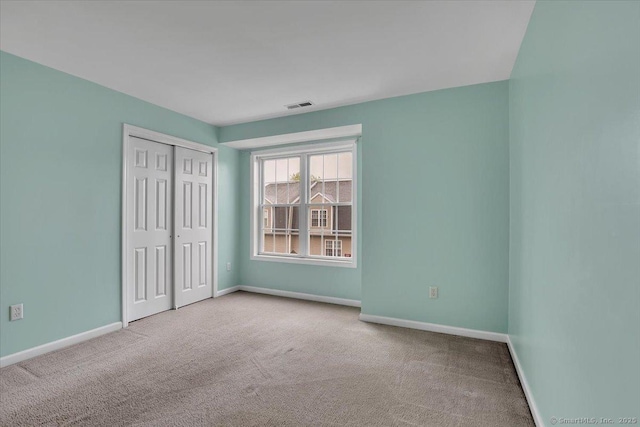 unfurnished bedroom featuring carpet, baseboards, and a closet