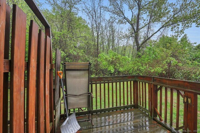 wooden terrace with a lawn and a wooded view
