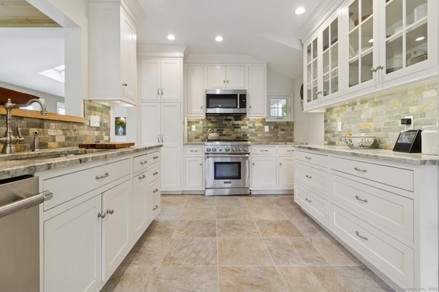 kitchen with stainless steel appliances, a sink, decorative backsplash, white cabinetry, and recessed lighting
