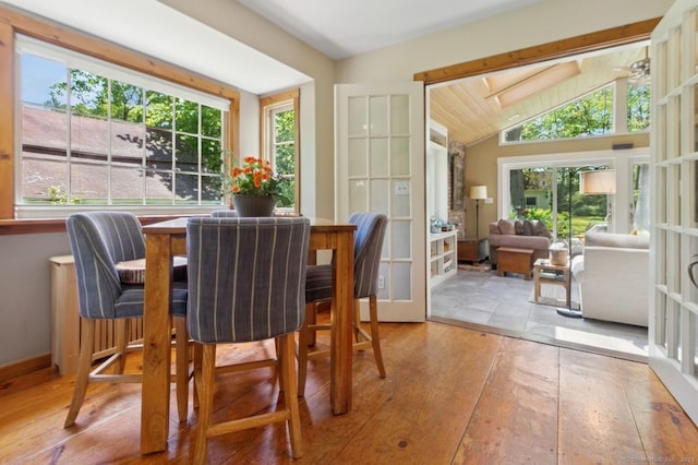 dining space with healthy amount of natural light, vaulted ceiling, and wood-type flooring