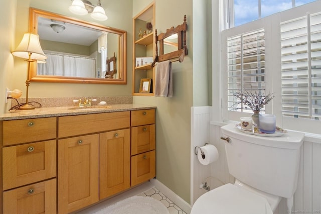 full bathroom featuring toilet, vanity, and wainscoting