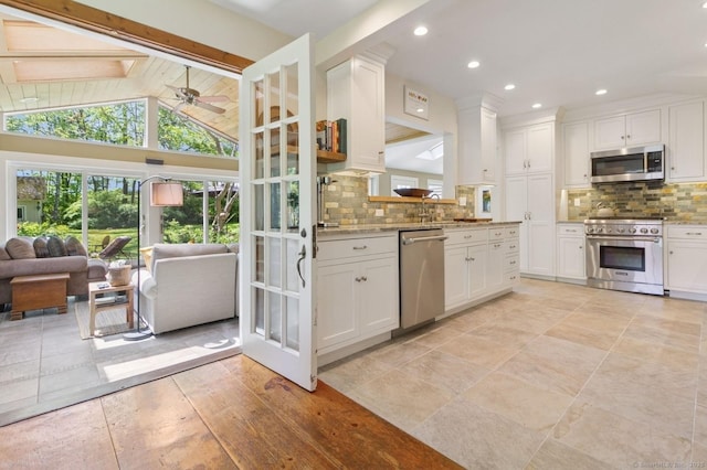 kitchen with stainless steel appliances, open floor plan, decorative backsplash, white cabinets, and recessed lighting
