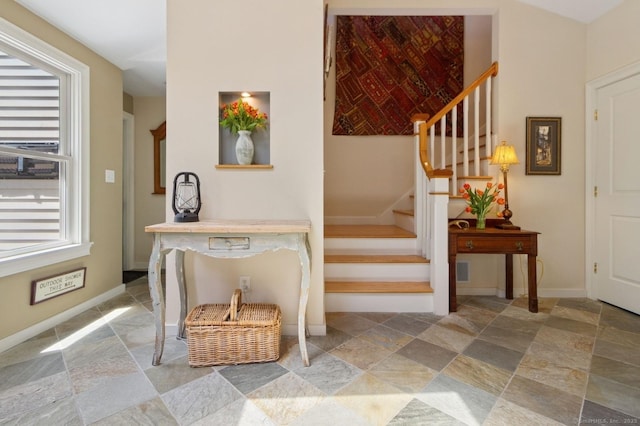 staircase featuring stone finish floors and baseboards
