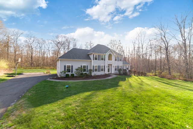 view of front of house with driveway, roof with shingles, and a front yard