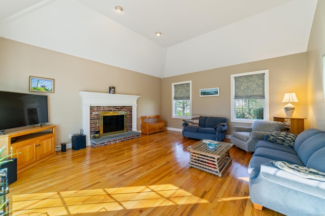living room featuring a fireplace, baseboards, light wood finished floors, and high vaulted ceiling