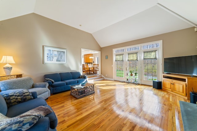 living area featuring lofted ceiling, light wood finished floors, and baseboards