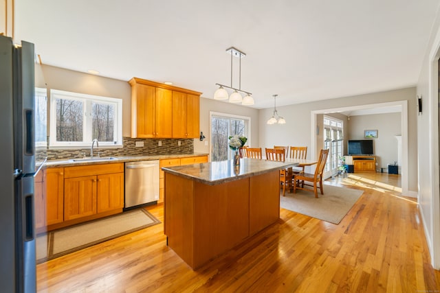 kitchen featuring dishwasher, a sink, freestanding refrigerator, a wealth of natural light, and a center island