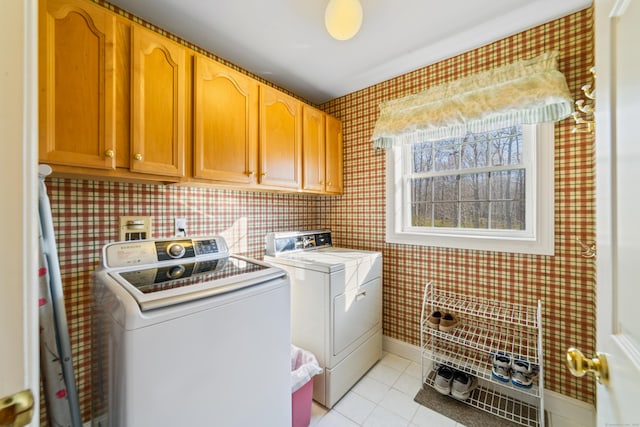 laundry room with light tile patterned flooring, washing machine and dryer, baseboards, wallpapered walls, and cabinet space