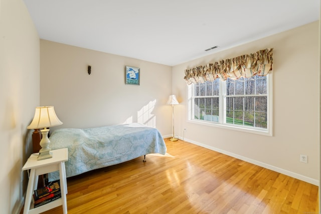 bedroom with wood finished floors, visible vents, and baseboards