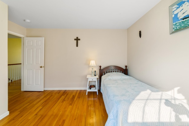 bedroom featuring light wood finished floors and baseboards