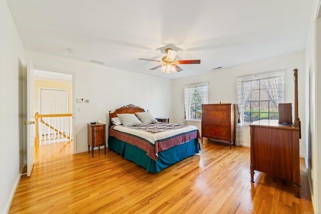 bedroom with light wood-type flooring, visible vents, a ceiling fan, and baseboards