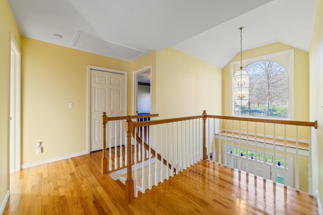 hall with attic access, baseboards, wood finished floors, and an upstairs landing