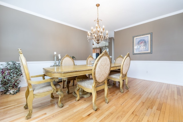 dining space featuring hardwood / wood-style flooring, baseboards, a notable chandelier, and crown molding
