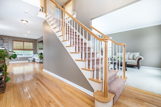 stairs with hardwood / wood-style floors, baseboards, and crown molding