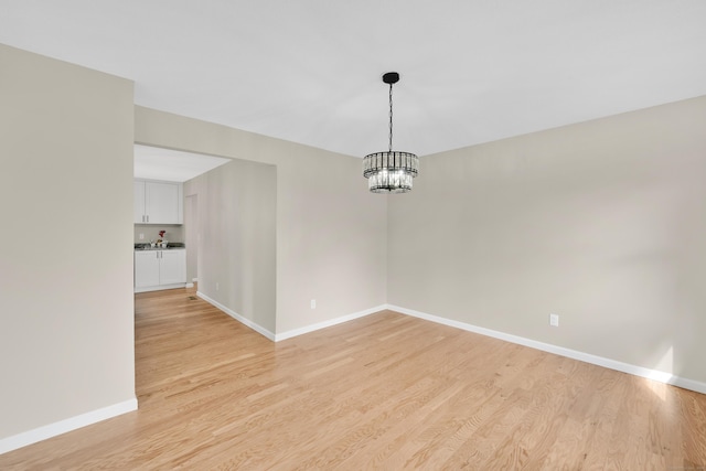 63 Rita Dr, Bristol, CT 06010 - unfurnished dining area with a chandelier, light wood-style flooring, and baseboards
