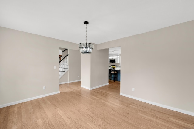 63 Rita Dr, Bristol, CT 06010 - unfurnished dining area with stairway, a chandelier, light wood finished floors, and baseboards