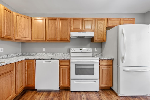 kitchen with under cabinet range hood, light stone countertops, wood finished floors, and white appliances