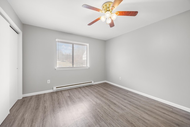 unfurnished bedroom with a baseboard radiator, wood finished floors, and a closet