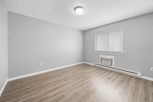 empty room with baseboards, wood finished floors, an AC wall unit, and baseboard heating