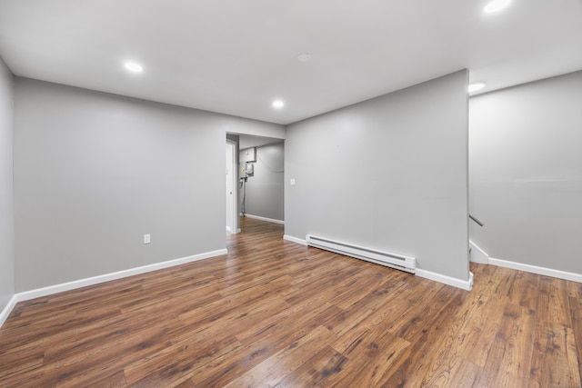 below grade area with a baseboard heating unit, wood finished floors, and baseboards