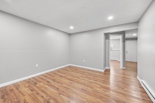 empty room with a baseboard heating unit, light wood-style flooring, baseboards, and recessed lighting
