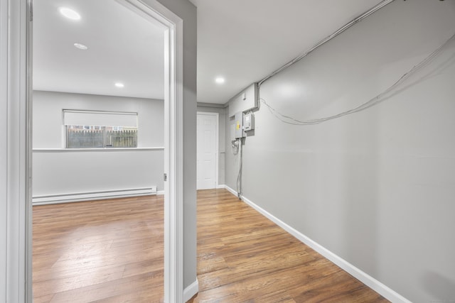 corridor featuring a baseboard heating unit, baseboards, wood finished floors, and recessed lighting