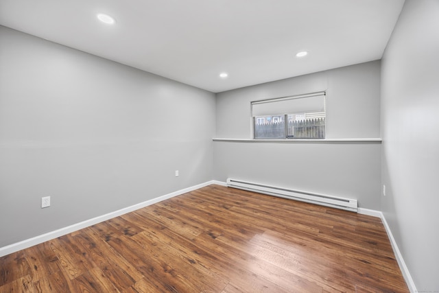 empty room featuring a baseboard radiator, wood finished floors, baseboards, and recessed lighting