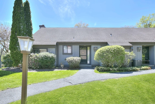 ranch-style home featuring board and batten siding, roof with shingles, and a front yard