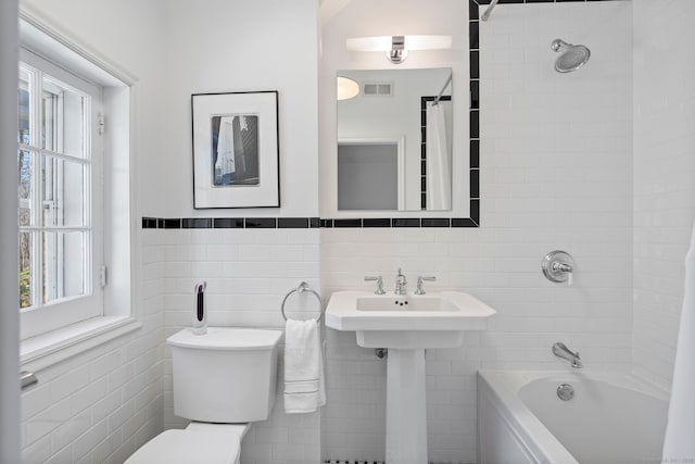 full bathroom with tile walls, visible vents, and bathing tub / shower combination