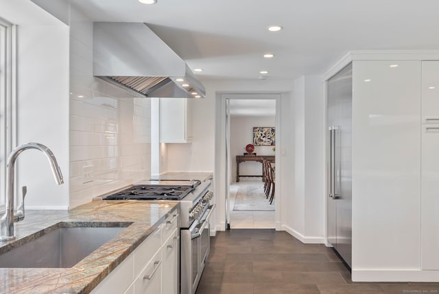 kitchen featuring a sink, white cabinetry, exhaust hood, light stone counters, and high quality appliances