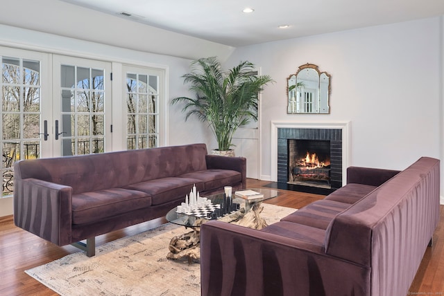 living area featuring visible vents, a brick fireplace, wood finished floors, and recessed lighting