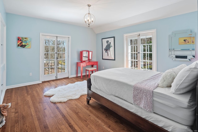 bedroom with wood finished floors, baseboards, and a notable chandelier