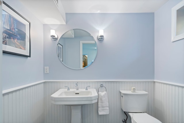 bathroom featuring wainscoting, a sink, and toilet
