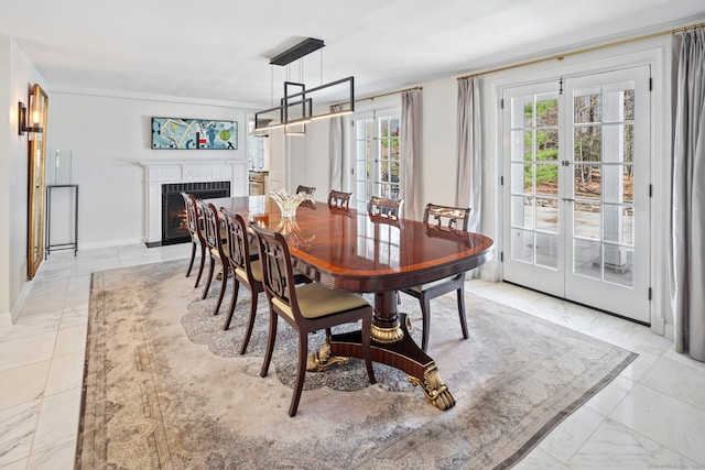 dining area featuring marble finish floor, a warm lit fireplace, and french doors