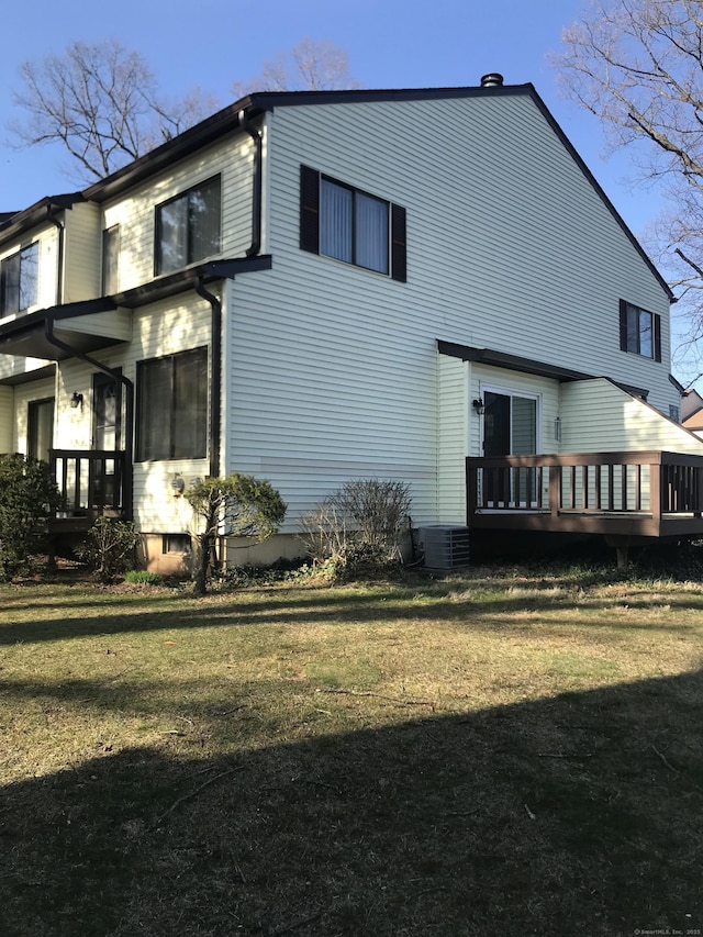 rear view of house with a wooden deck and a lawn