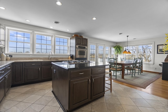 15 Buckingham Ave, Old Saybrook, CT 06475 - kitchen featuring appliances with stainless steel finishes, light tile patterned floors, recessed lighting, a kitchen island, and a kitchen breakfast bar