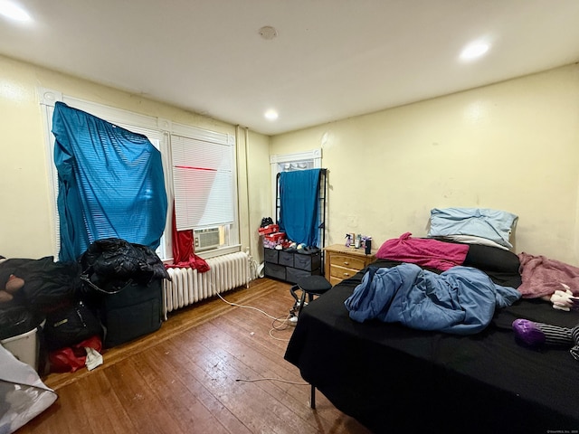 bedroom with wood-type flooring, radiator heating unit, recessed lighting, and cooling unit